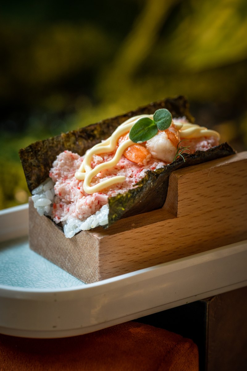 Temaki con riso, granchio e alga nori servito su base in legno